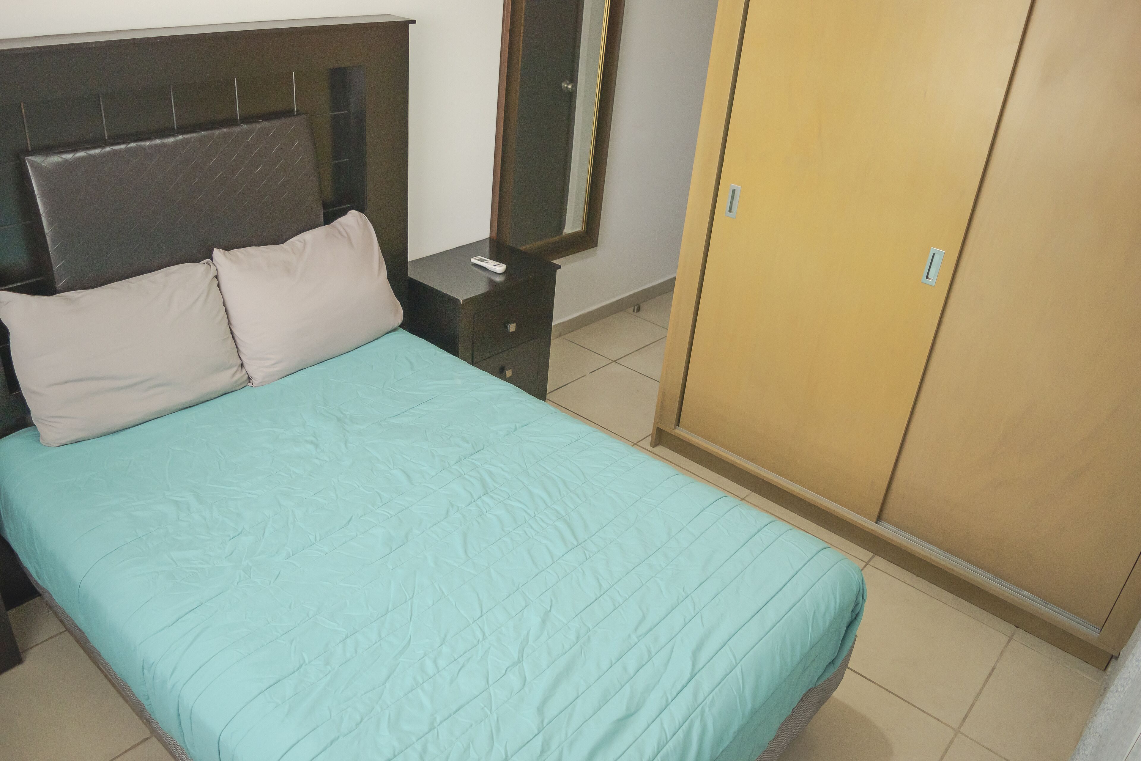 Ein Schlafzimmer mit einem Bett, einem Nachttisch, einem Spiegel und einem Kleiderschrank.
