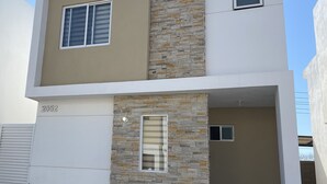 A modern two-story building with a stone facade and a flat roof. - Casa Almar (Mazatlán)