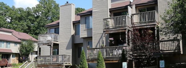 A multi-story residential building with balconies, a stone facade, and a sign indicating reserved parking.