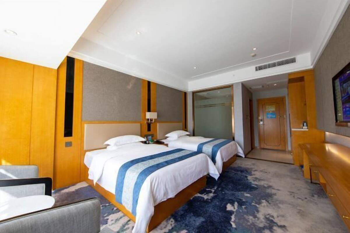Ein Hotelzimmer mit zwei Betten, einem Schreibtisch, einem Stuhl und einer Badezimmertür.