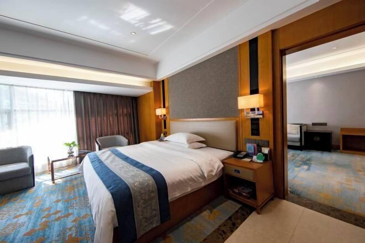 Ein Hotelzimmer mit einem großen Bett, einem Schreibtisch, einem Sessel, einem Nachttisch und einem Spiegel.