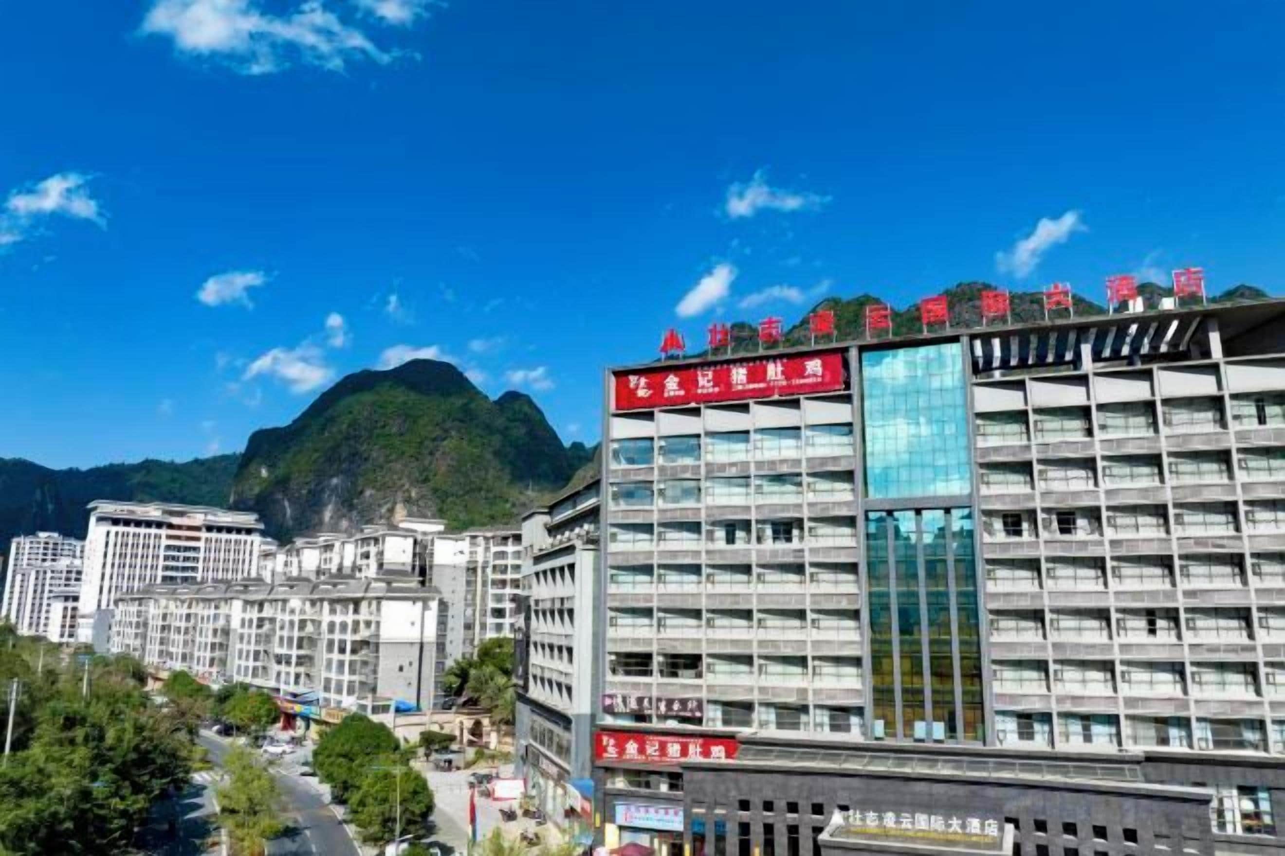 A multi-story hotel with a modern facade, large windows, and a prominent red sign on the top.