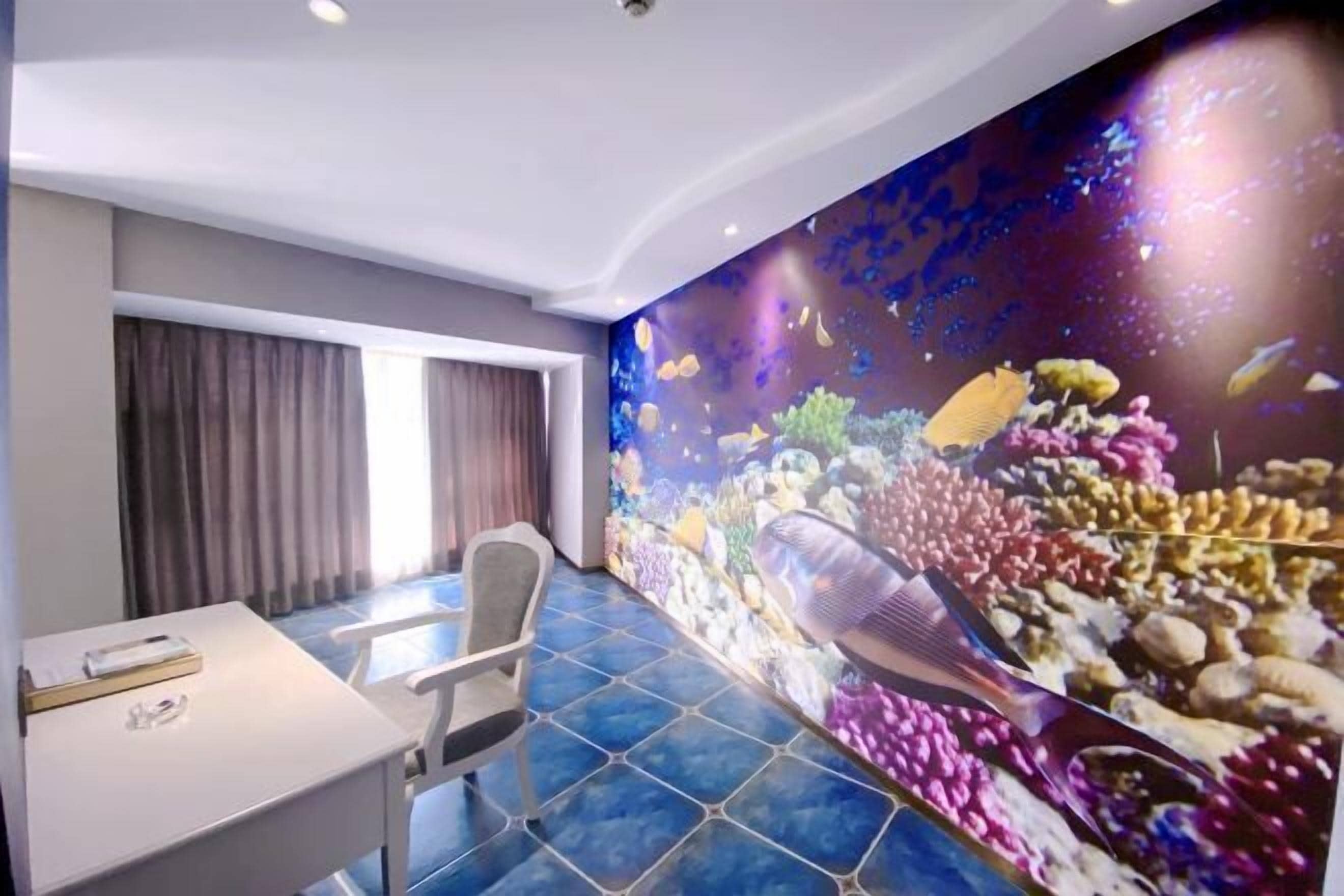 Une pièce avec un grand mur occupé par un aquarium, un bureau blanc et une chaise.