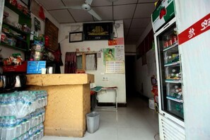 A narrow shop with shelves stocked with various items, a refrigerator, and a counter with stacked goods. - Jingpai Hotel (Nanchang)