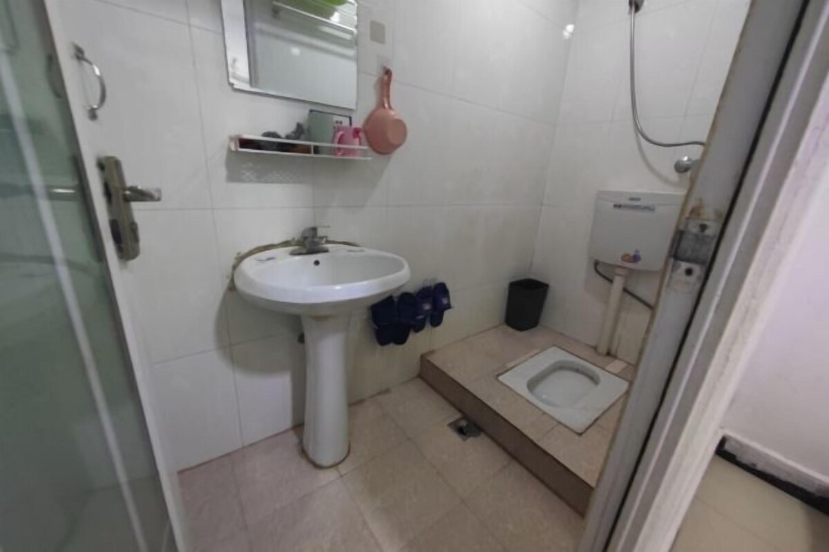 A bathroom with a pedestal sink, a toilet, a shower, and a mirror.