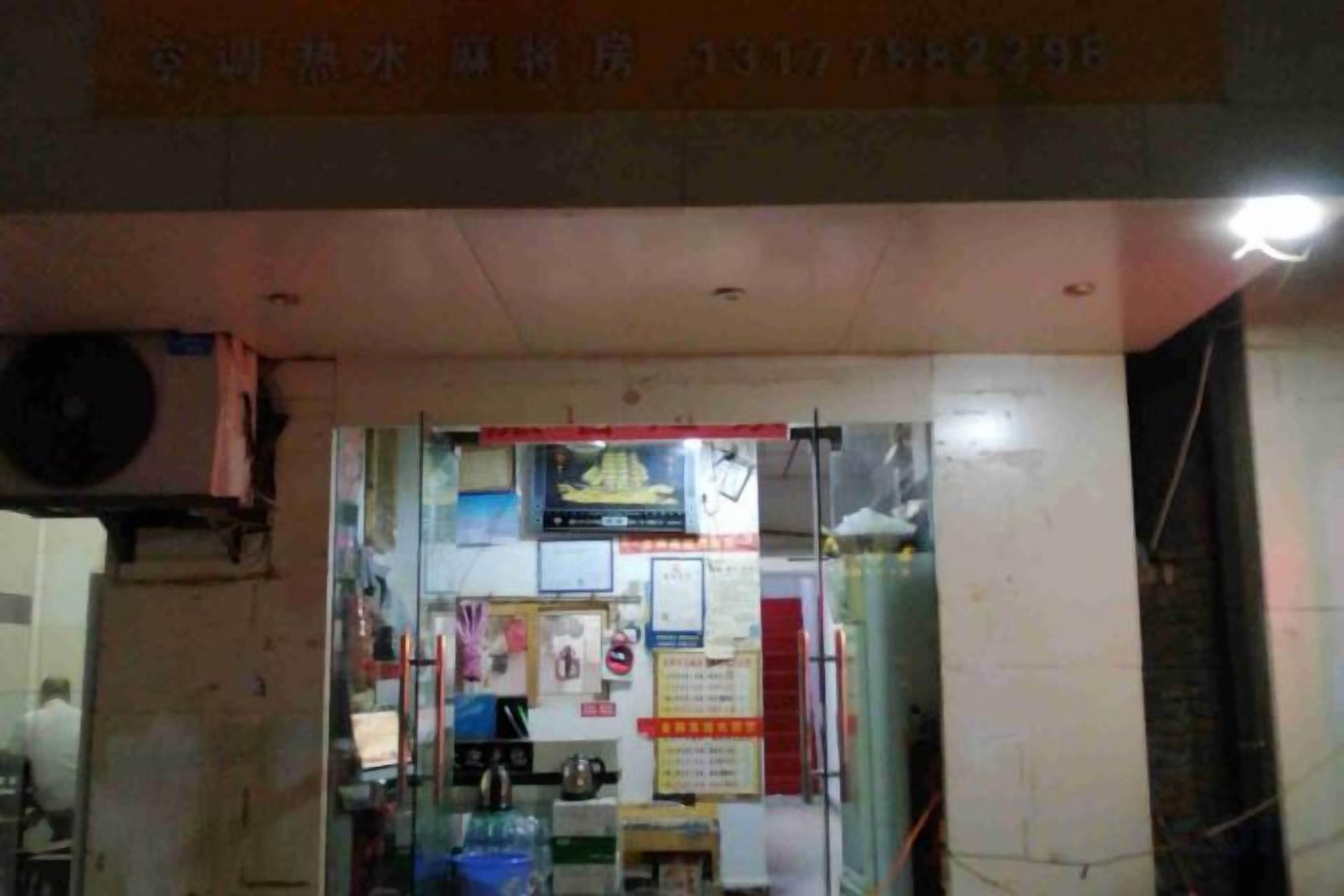 A small shop with a glass front, various signs, and a visible door.