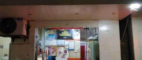 A small shop with a glass front, various signs, and a visible door.