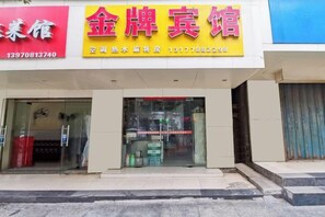 A hotel with a yellow signboard, glass entrance, and a visible interior with various items. - Jingpai Hotel (Nanchang)