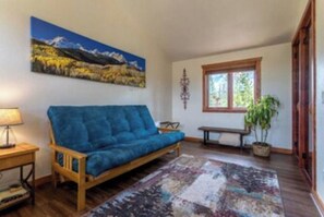 Relax in this inviting living room with a sofa, patterned rug, and a beautiful mountain landscape painting.