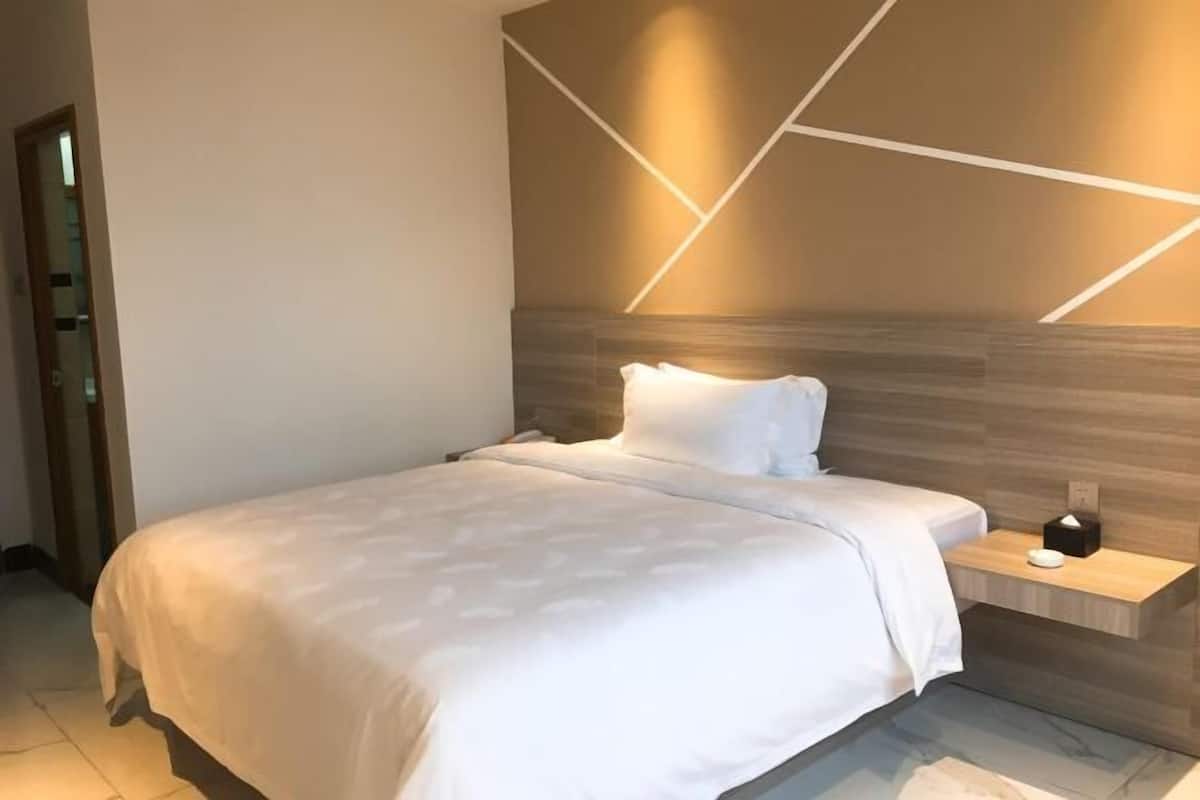 Relax in a serene space with a large bed, bedside table, and geometric light fixture.