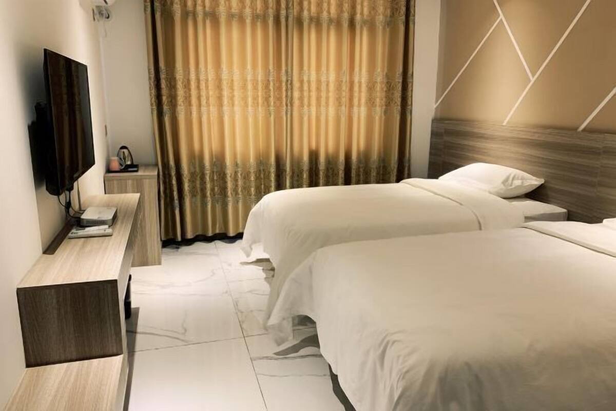 Una habitación de hotel con dos camas, un televisor, un escritorio y una cortina.