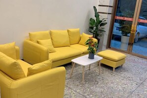 Un sofá amarillo con una mesita y una planta en maceta.