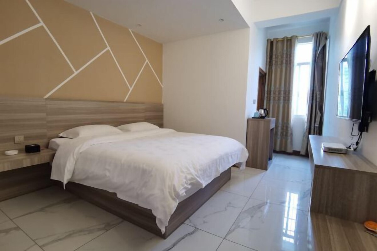 Une chambre d’hôtel comprenant un lit, une table de chevet, une télévision et une salle de bain avec douche.
