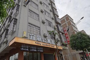 Un edificio de varios pisos con un letrero que dice 'Yiling Apartment Hotel' y un banderín rojo que indica 'Prohibido Estacionar'.