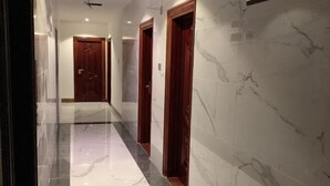 Un pasillo con suelo de mármol y puertas de madera que conduce a una habitación con ventilador de techo.