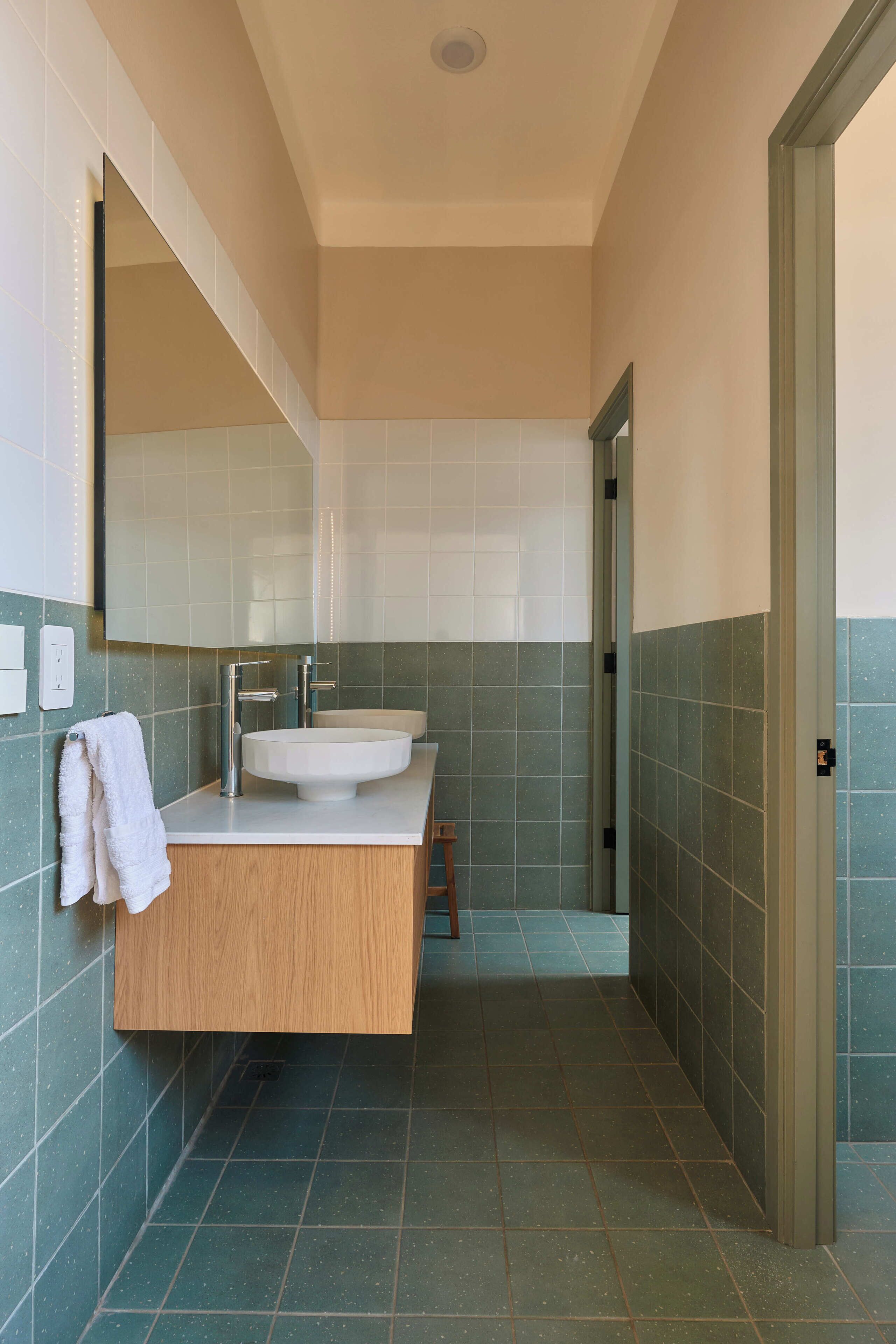 Un baño con lavamanos, espejo y toallero.