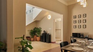 Un coin repas avec une table dressée pour quatre personnes, un escalier et des plantes en pot.