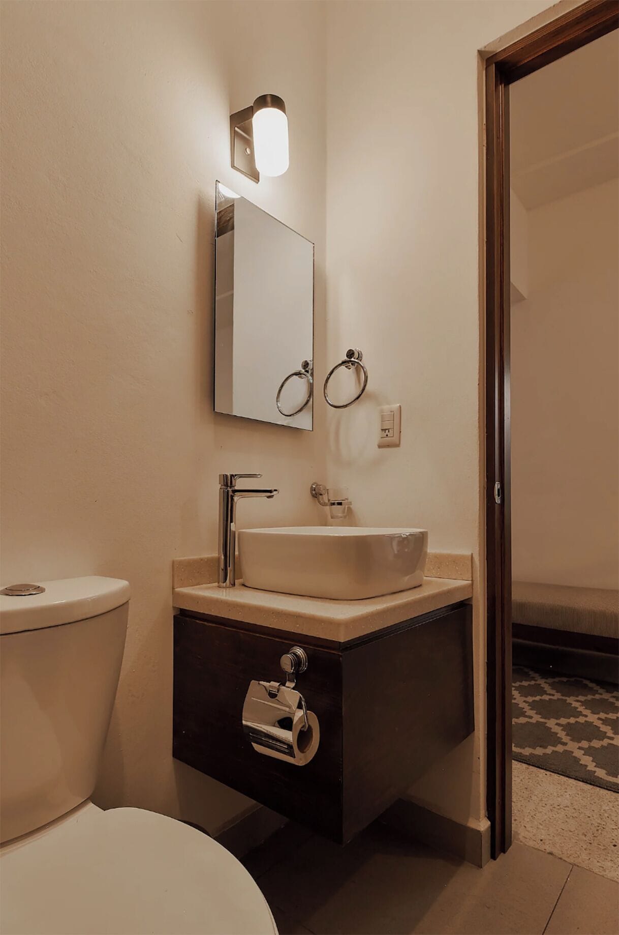 Een badkamer met een wit wastafel, een spiegel, een handdoekhouder en een toilet.