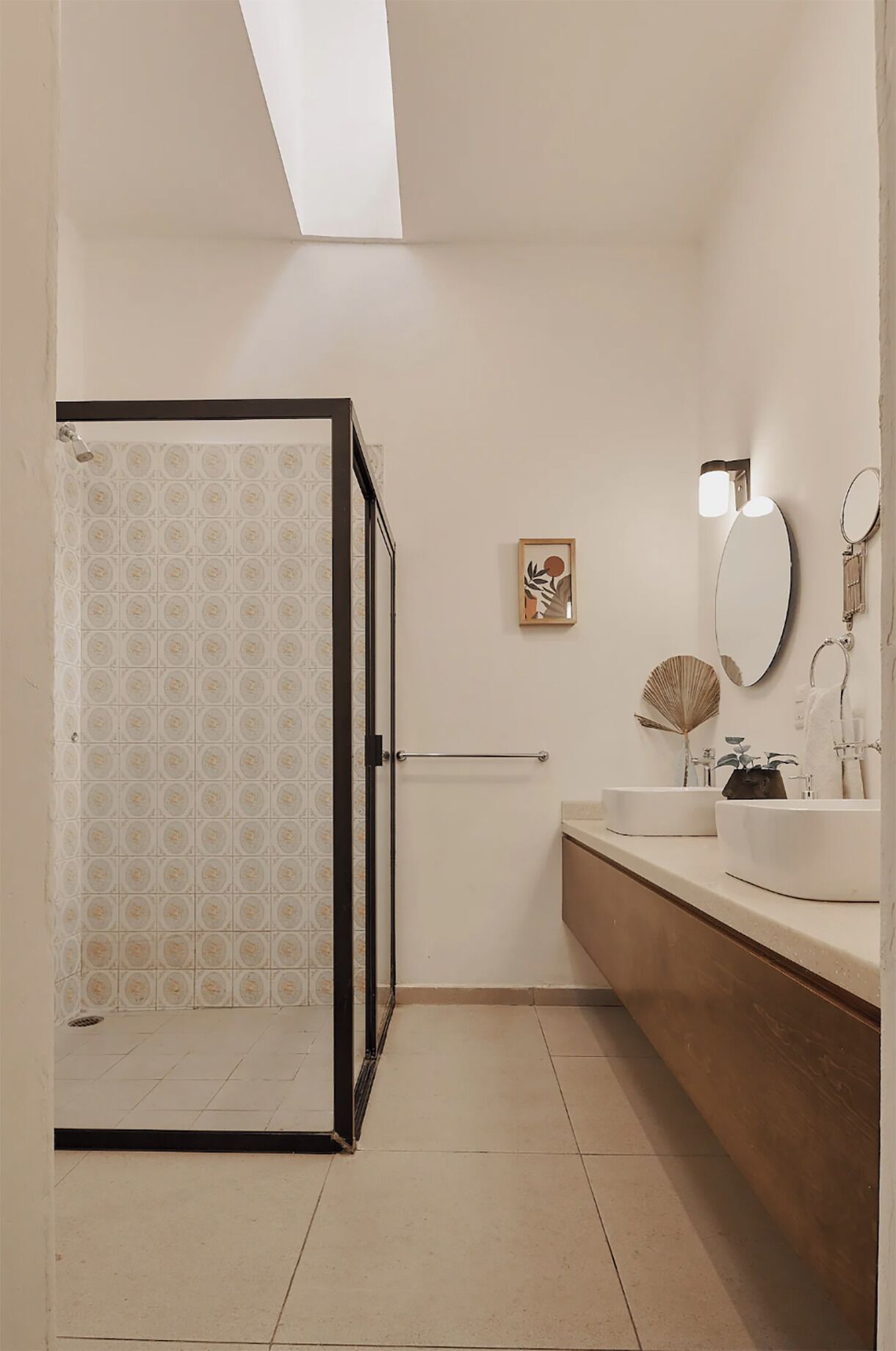 Ein modernes Badezimmer mit Dusche, zwei Waschbecken, einem großen Spiegel und einem gerahmten Kunstwerk an der Wand.