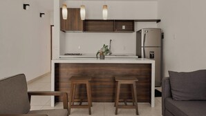 Une cuisine compacte dotée d’un îlot central, de meubles en bois et d’un réfrigérateur encastré.