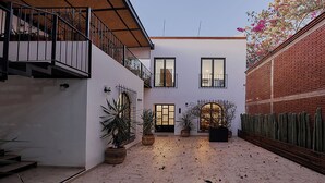 Une cour avec un bâtiment blanc, un mur de briques et un jardin de cactus.