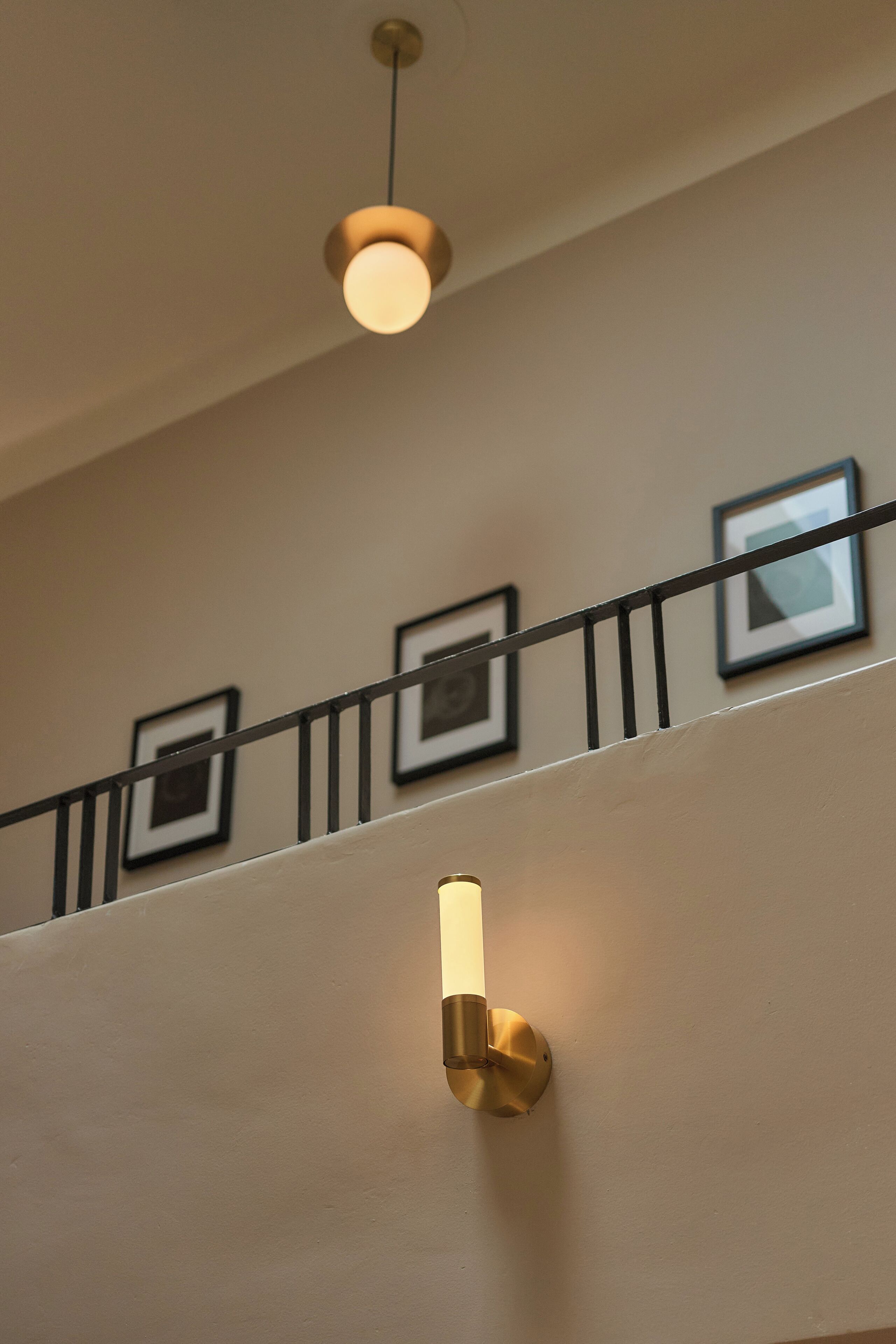 Un escalier avec un luminaire et des tableaux encadrés accrochés au mur.
