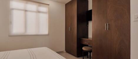 Un dormitorio con cama, escritorio y armario.