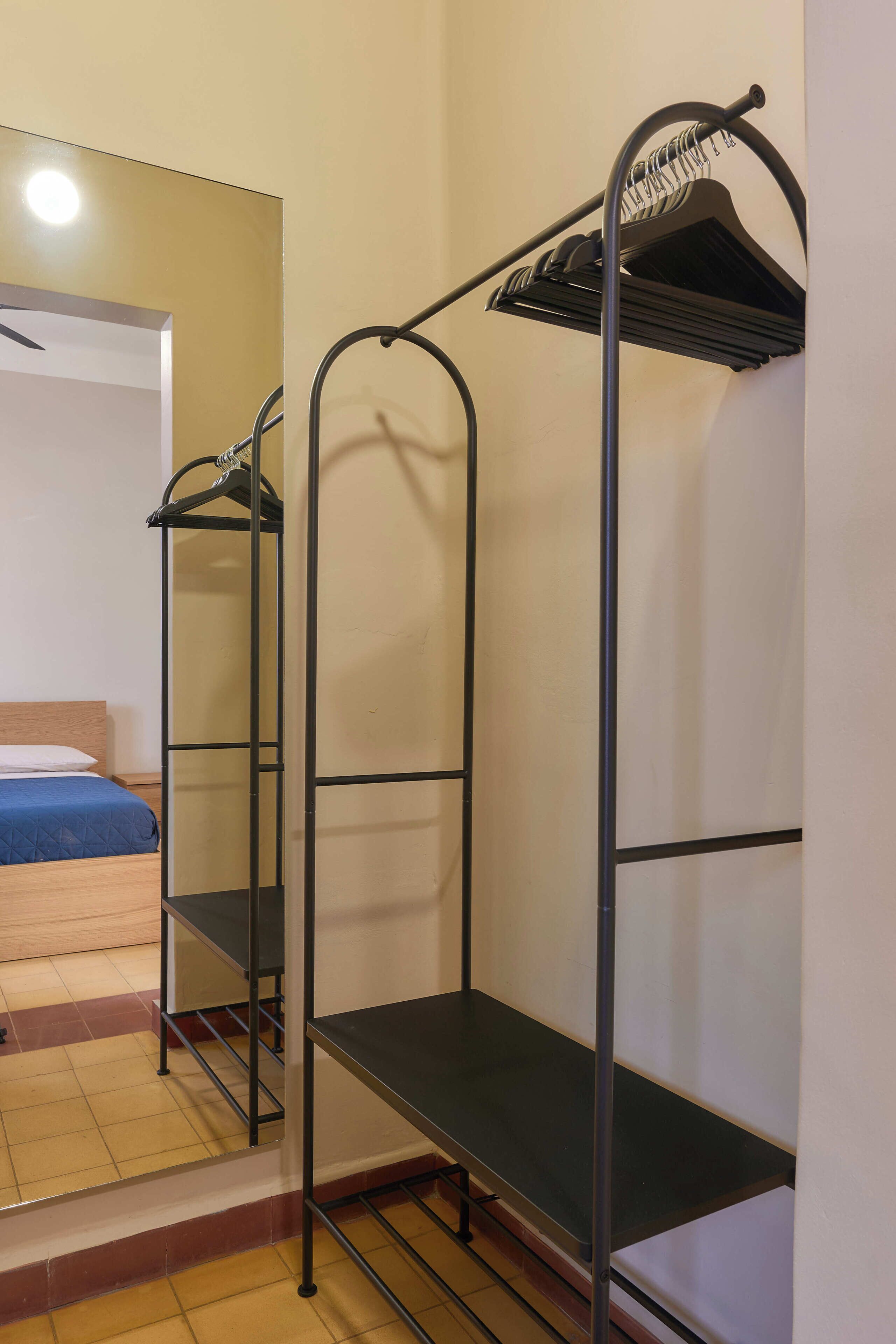 A room with bunk beds, a metal wardrobe, and a bed with a blue blanket.