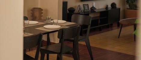 A dining area with a table set for four, a television mounted on the wall, and a potted plant.