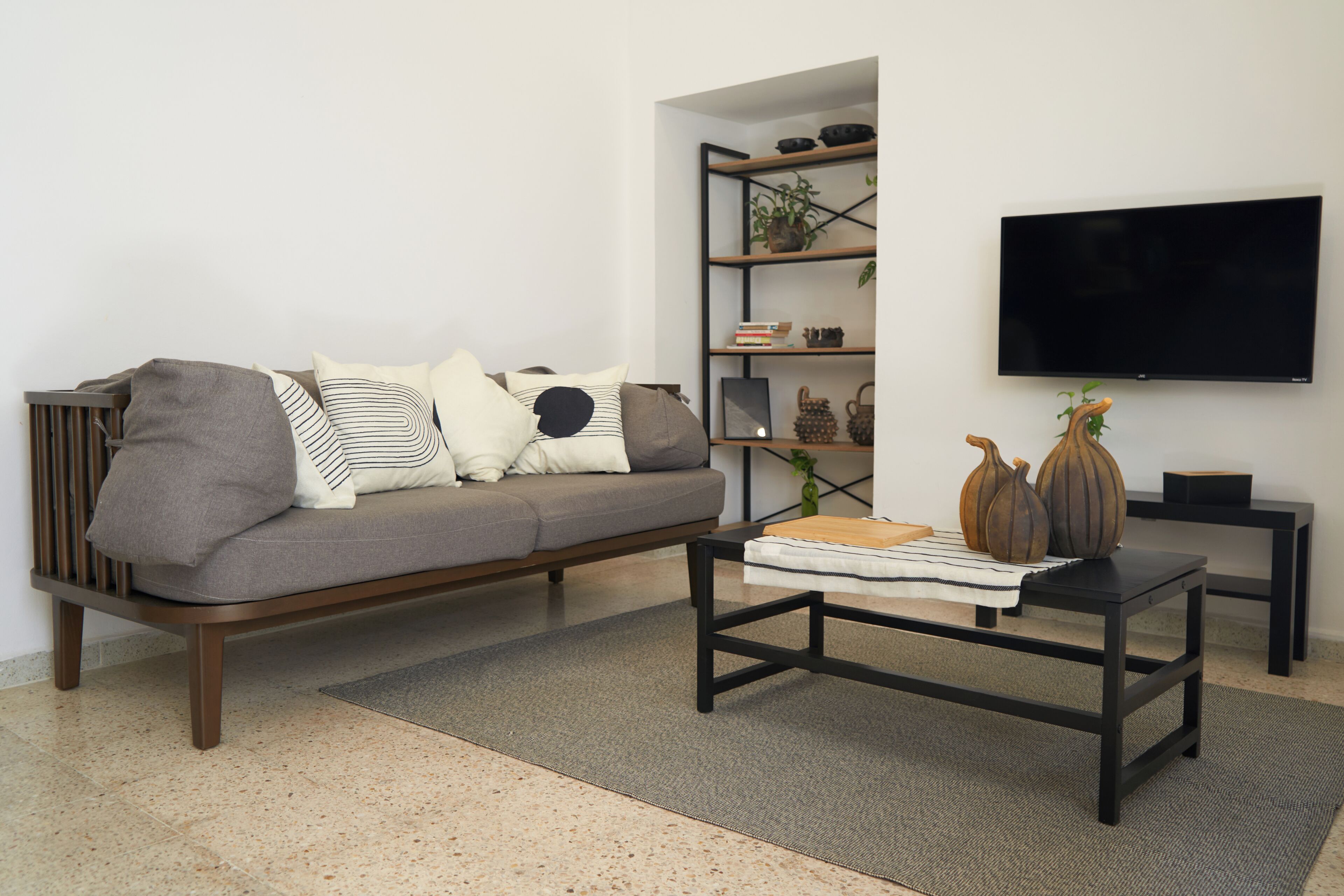 A living room with a sofa, a coffee table, a bookshelf, and a flat-screen TV.