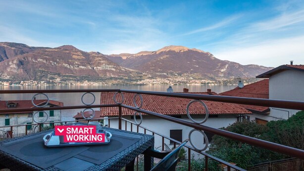 A balcony with a view of mountains and a lake, a table with a tray, and a sign that reads "SMART WORKING". - Casa Giulia by Wonderful Italy (Lezzeno)