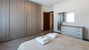 A bedroom with a large wardrobe, a bedside table, a mirror, and two folded towels on the bed. - Casa Giulia by Wonderful Italy (Lezzeno)