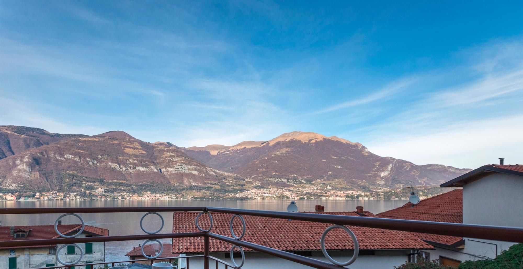 A balcony with a view of mountains and a lake, a table with a tray, and a sign that reads "SMART WORKING".