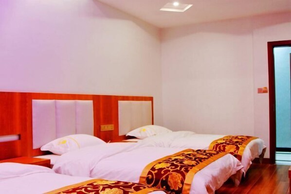 Una camera d'albergo con due letti, una testiera in legno e una porta a destra.