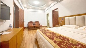 Una habitación de hotel con cama, escritorio, televisión y una lámpara en el techo.
