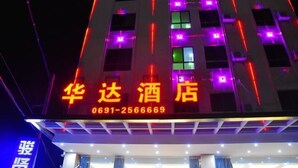 Un hotel con señalización iluminada en amarillo y rojo, que muestra un número de contacto.