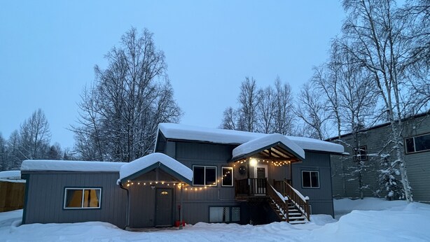 A two-story house with a covered porch and a staircase leading to the entrance. - Scenic Alaskan cabin in the mountains (Anchorage)