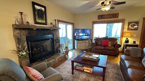 A cozy living room with a stone fireplace, comfortable seating, a television, and a 'Welcome' sign. - Red Wolf Lodge-Blue Ridge views, wraparound deck, outdoor fireplace (Dillard)