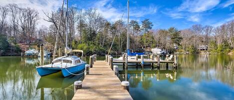 A wooden dock extending into calm water with boats docked at the end.