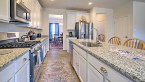 A modern kitchen with granite countertops, stainless steel appliances, and white cabinetry.