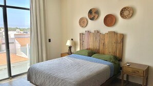 Une chambre à coucher avec un lit, une tête de lit en bois, des tables de chevet et des assiettes décoratives accrochées au mur.