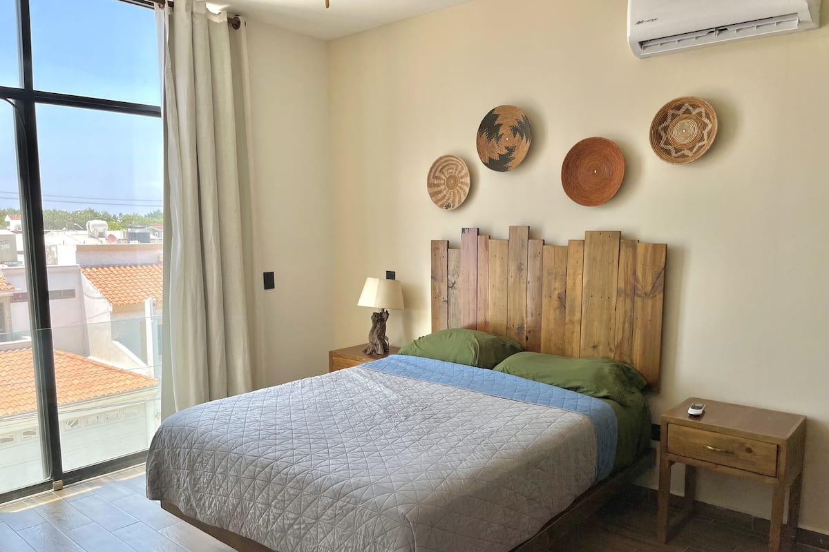 A bedroom with a bed, wooden headboard, bedside tables, and decorative plates on the wall.