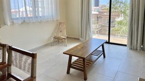 Une pièce spacieuse avec une grande fenêtre, un banc en bois et une table.