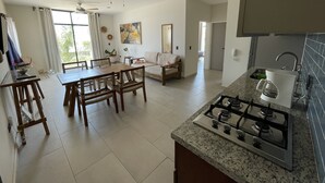 Une cuisine spacieuse équipée d’une cuisinière à gaz, d’un coin repas avec des chaises en bois et d’un ventilateur de plafond.