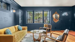 Ein Zimmer mit einer dunkelblauen Wand, einem gelben Sofa, einem Glastisch und einem Teppich mit ZEBRA-MUSTER.