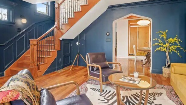 Ein modernes Wohnzimmer mit einer Holztreppe, einem Glastisch und einem gelben Sofa.