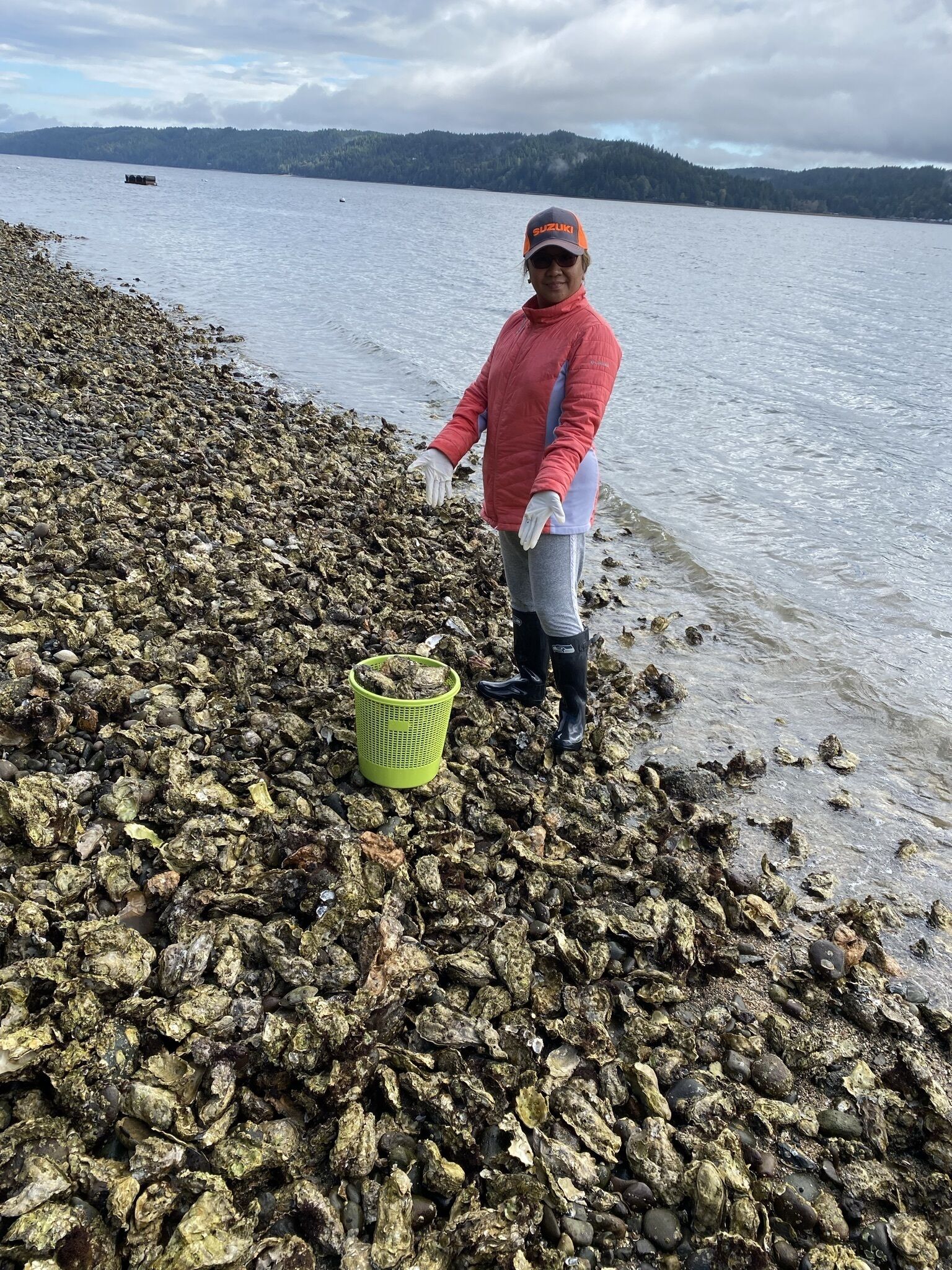 A person standing on a rocky shore with a basket of oysters.