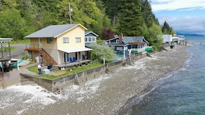 A coastal property with a house, a covered porch, and a view of the sea.