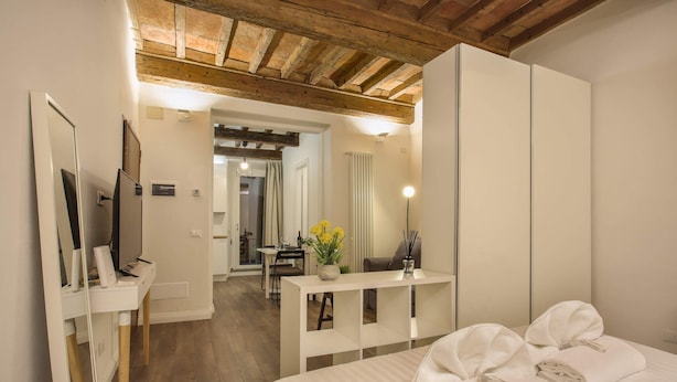 A hotel room with a bed, a desk, a mirror, and a wardrobe. - La Sinagoga Suite (Florence)