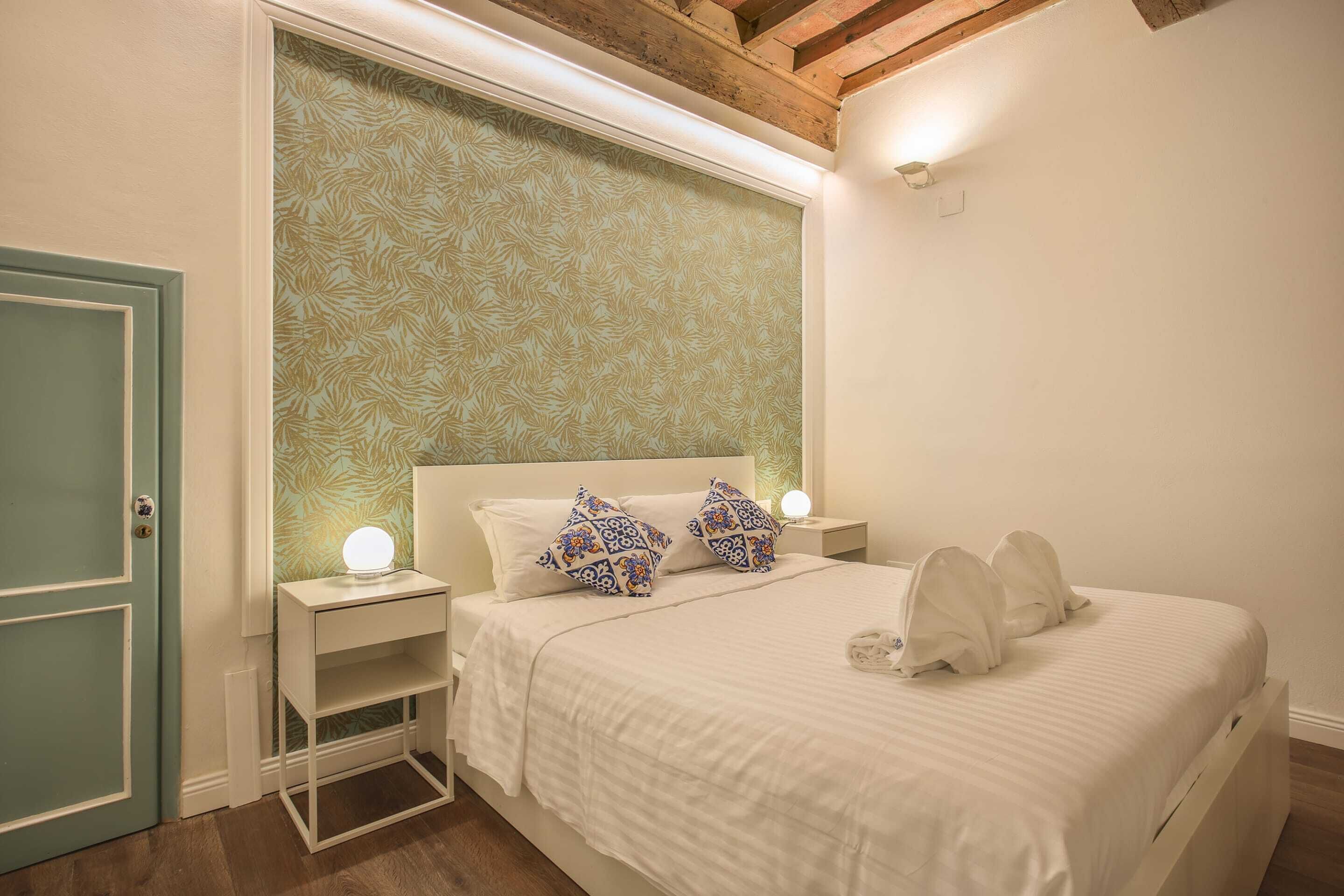 A bedroom with a bed, nightstands, and a door.